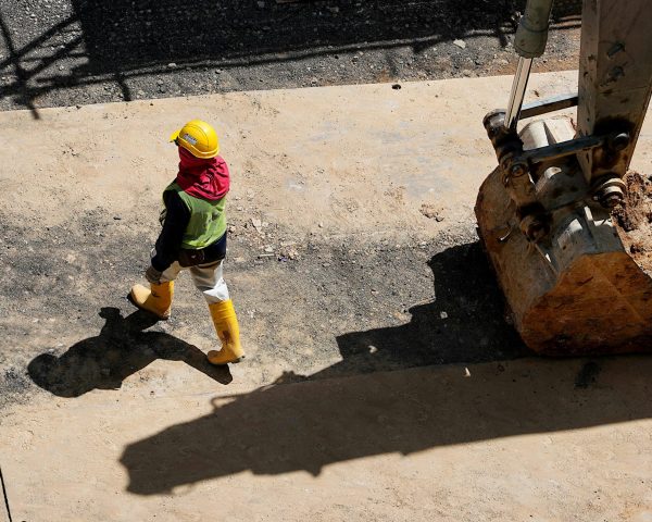 Overhead view of a construction worker walking beside a large excavator.